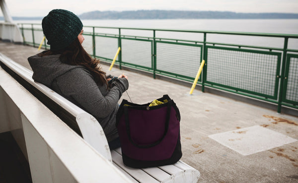 A person at a bench on a ferry knitting out of the Swift.